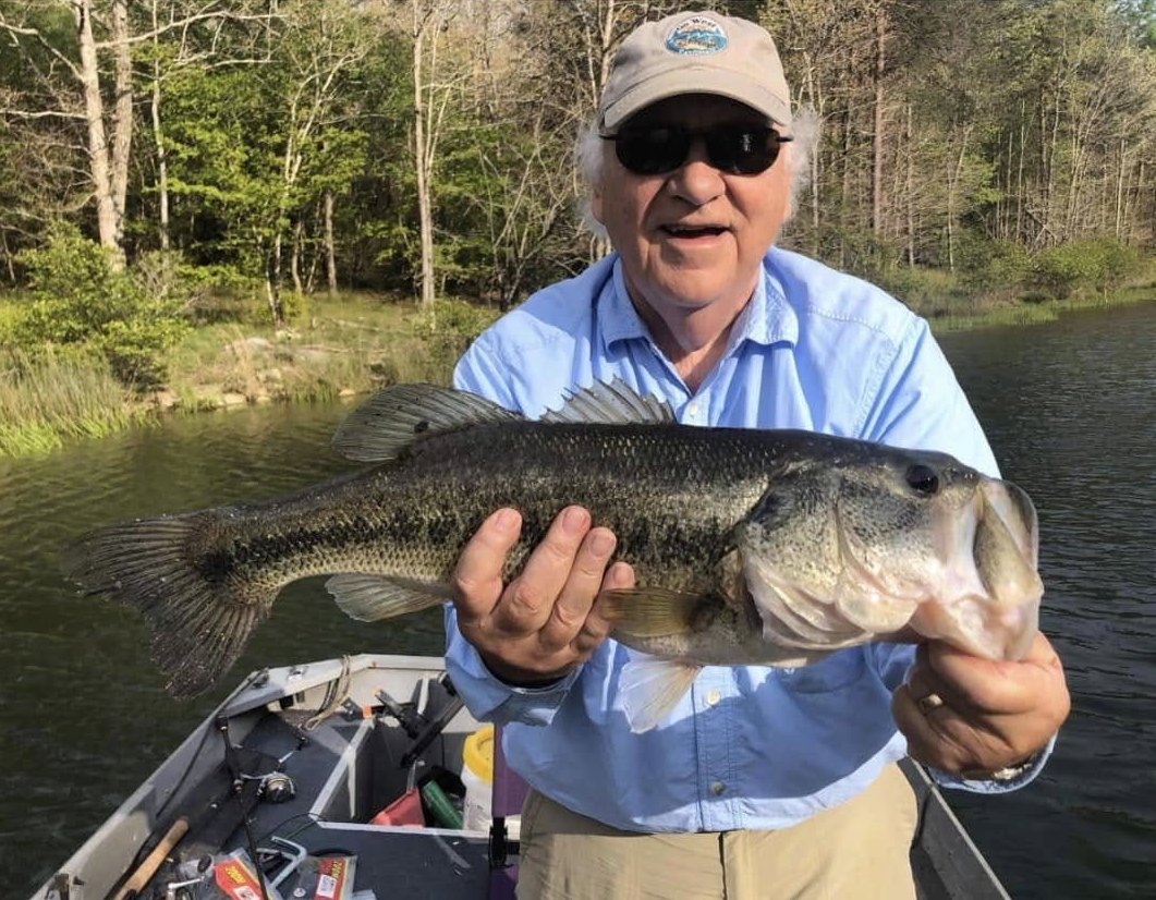 Older angler holding a largemouth bass on the boat