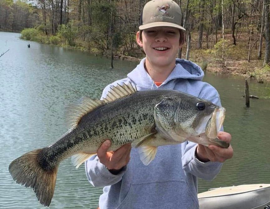 Young angler holding a largemouth bass at the pond