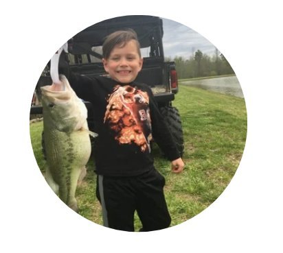 Young angler holding a largemouth bass by a pond